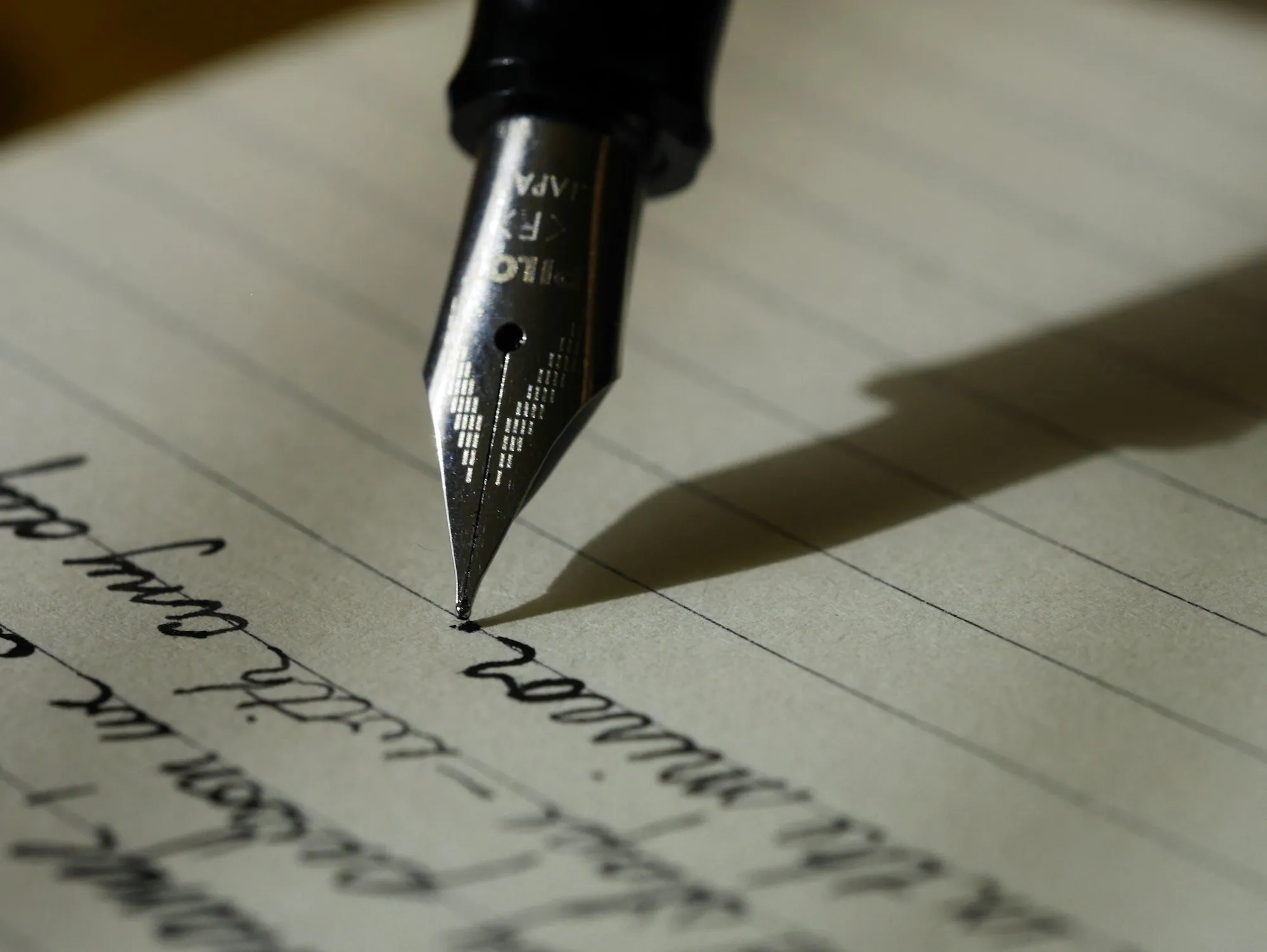 An open notebook and pen on a wooden desk.