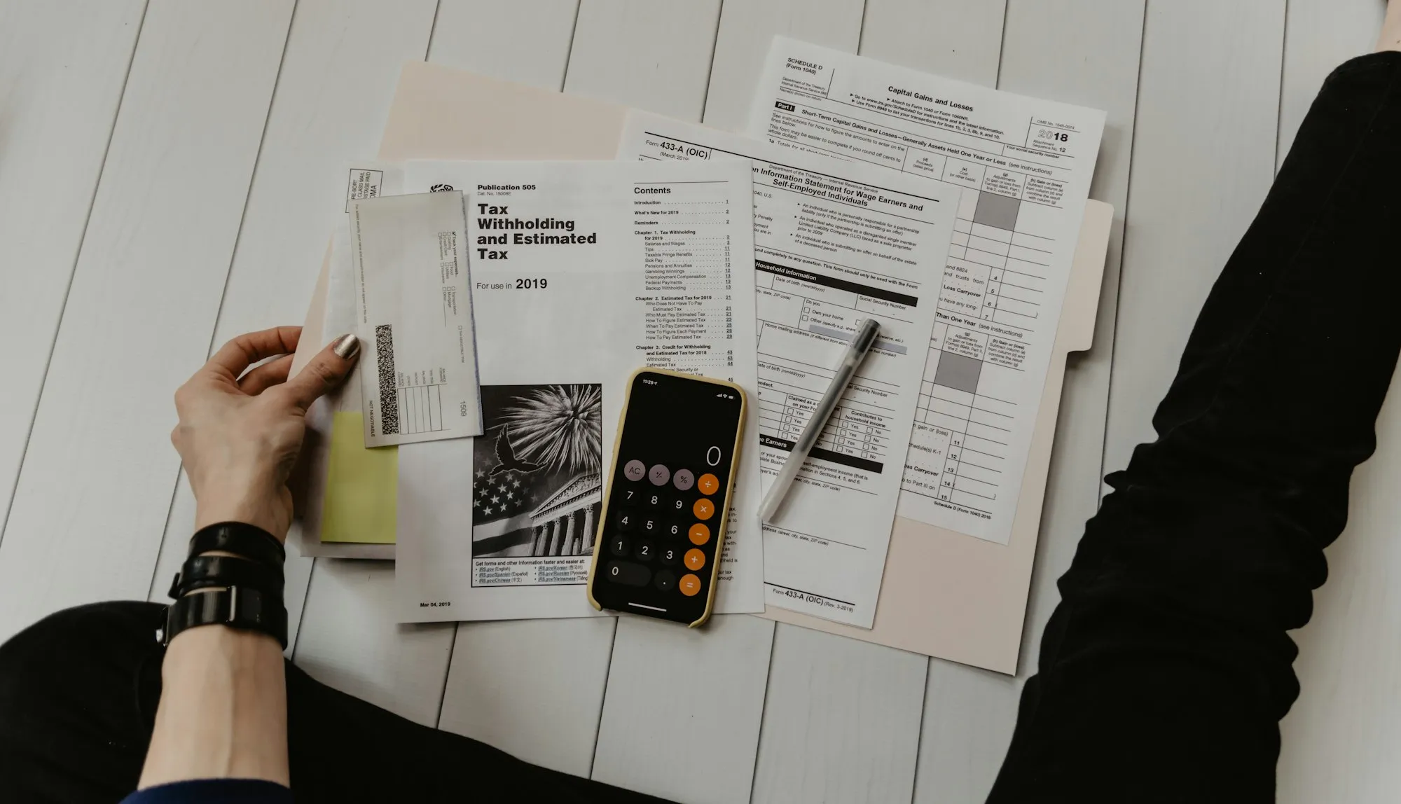 Printed tax and finance forms spread across a desk beside a calculator.